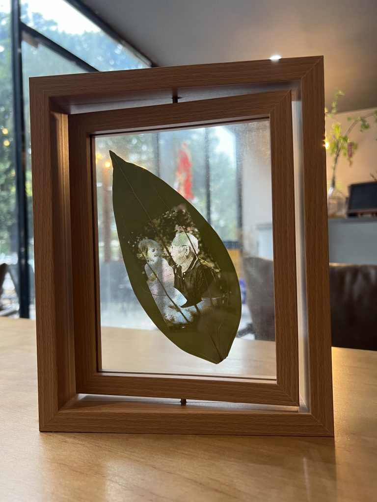 Granddad with granddaughter picture on leaf in rectangle photo frame.