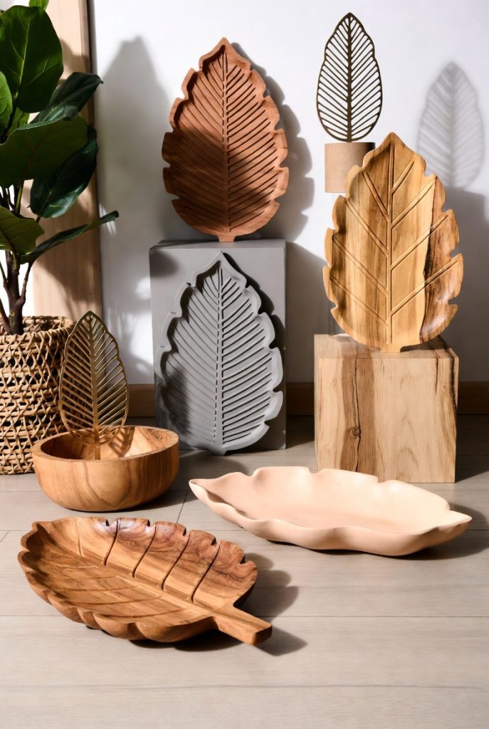 Handcrafted wooden and ceramic leaf-shaped trays and bowls displayed on rustic surface with large plant, perfect botanical leaf decor gifts.