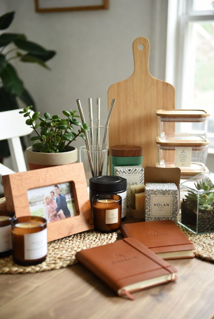 Collage of heartfelt gifts for mother including custom photo frame, engraved necklace, handmade soap, scented candles, cozy blanket, floral mug, wooden cutting board, and fresh flowers arranged on rustic wooden surfaces.